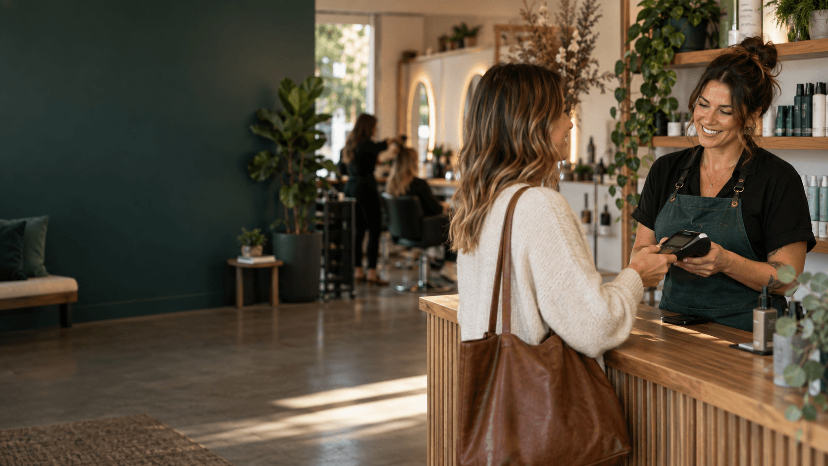 A salon owner accepting a payment from a customer in a modern service studio